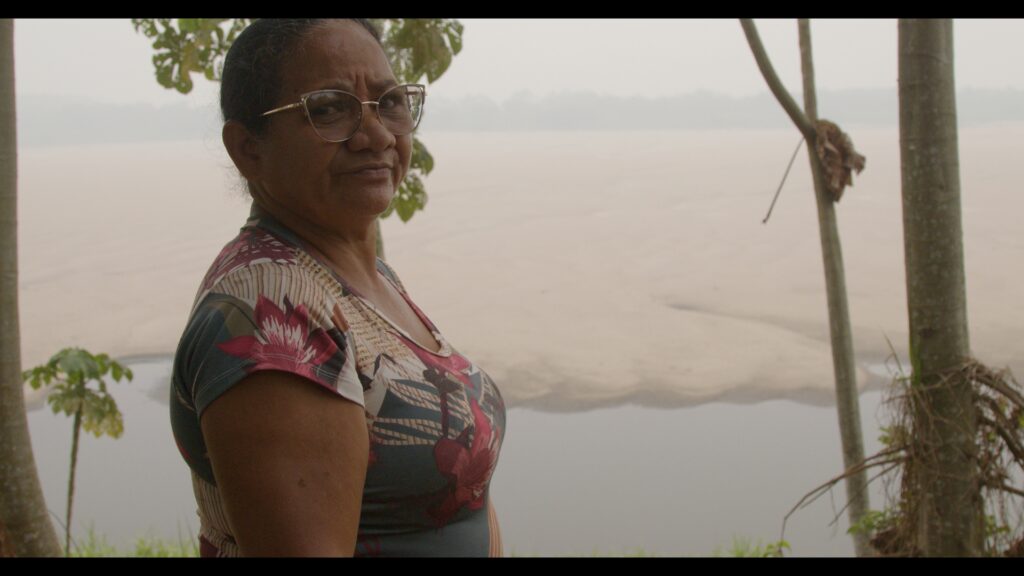 Maria Nilce da Silva, atingida da comunidade de Brasileira, ao fundo o Rio Madeira seco e coberto de fumaças em setembro de 2024. Foto: Raissa Dourado / MAB
