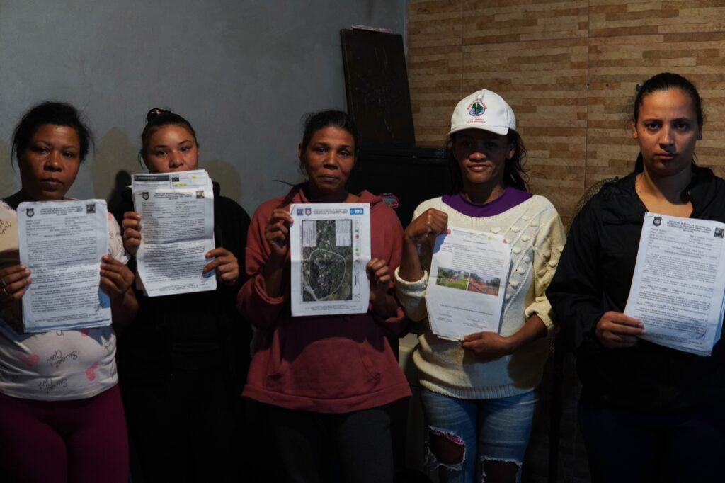 Jamile Alves (ao centro) e outras atingidas do bairro Boiçucanga com seus laudos da Defesa Civil, que indicam risco de desabamento de suas casas. Foto: Arthur Macfadem / MAB
