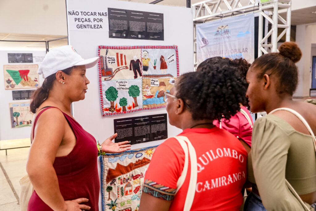 Fernanda Maria, atingida de São Paulo, explica a arpillera para outros militantes na Cúpula dos Povos. Foto: Nivea Magno / MAB